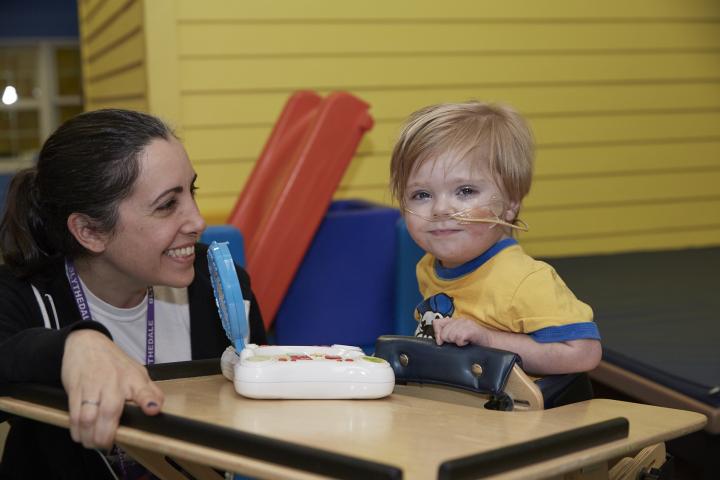 Zach (3 years old) at PT, smiling and playing a game.