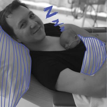 Dad holding newborn son kangaroo style while he sleeps