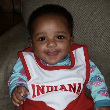 photo of 9 month old baby sitting and smiling at camera