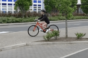 A girl is biking on a road.